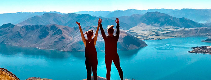 Zwei Menschen auf einem Berggipfel mit Blick auf einen See