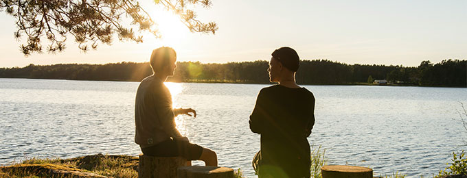 Zwei Menschen im Gespräch am See bei Sonnenuntergang